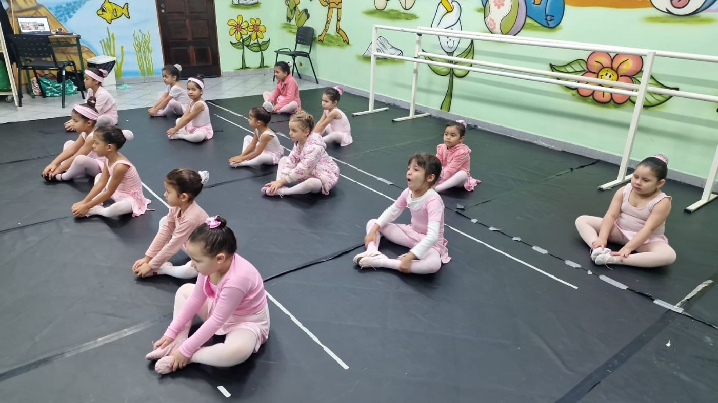 Aula de balé com meninas sentadas no chão da sala