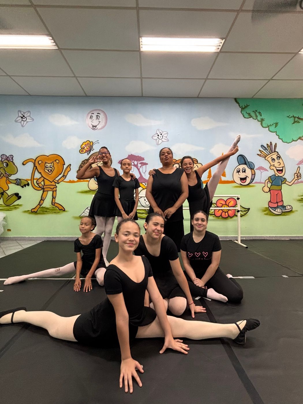 Turma de balé posando na sala com mural colorido